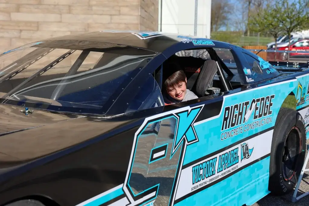 A child smiles from the driver's seat of Adam Casari's race car.